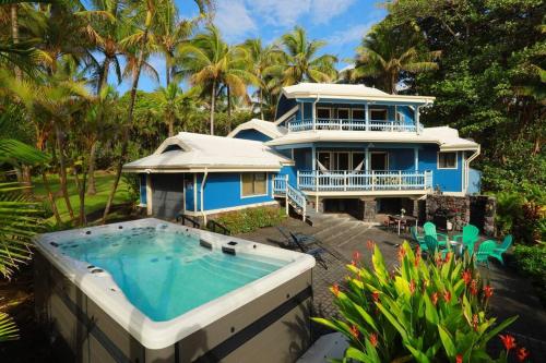 a blue house with a swimming pool in front of it at kehena black sand beach house - ocean view swim spa in Pahoa