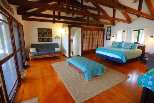 a bedroom with a bed and a couch in it at kehena black sand beach house - ocean view swim spa in Pahoa