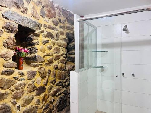 ein Badezimmer mit ebenerdiger Dusche neben einer Steinmauer in der Unterkunft Casa de piedra en Ollantaytambo in Ollantaytambo