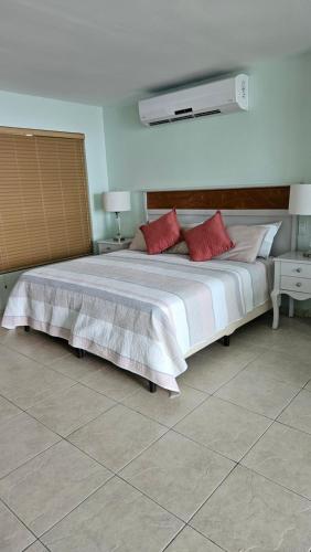a bedroom with a large white bed with red pillows at Solarium Studio Apartment at Coronado Bay Oceanfront in Playa Coronado