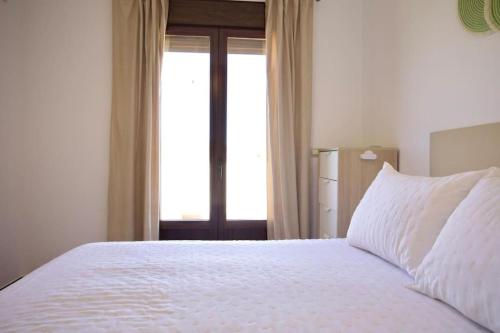 una camera da letto con un grande letto bianco con una finestra di Casa Carmen a Nerja