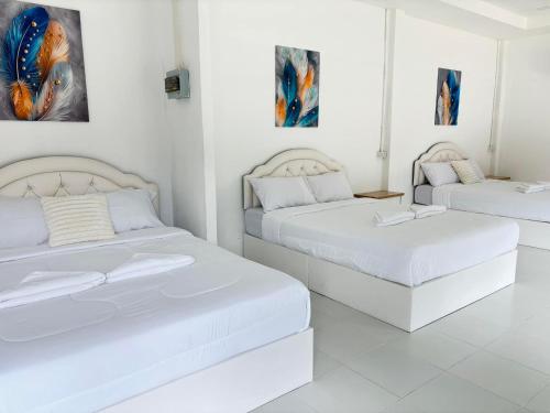 two beds in a room with white walls at ชิลชิลขนอมพูลวิลลา in Ban Thong Ching