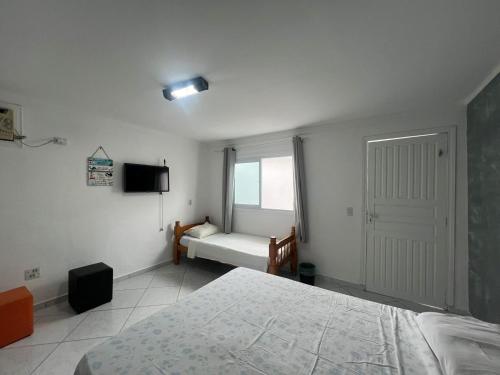 a white bedroom with a bed and a window at Boas Vindas in Guarujá