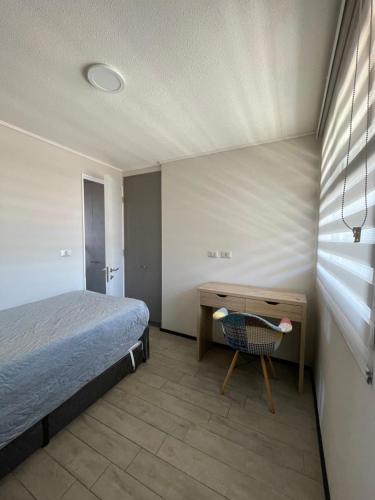 ein Schlafzimmer mit einem Bett und einem Schreibtisch mit Stuhl in der Unterkunft Departamento cerro barón in Valparaíso
