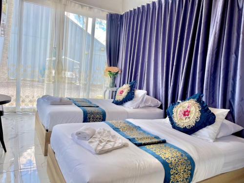 three beds in a room with purple curtains at Banjert Villa Beach@สิชล in Ban Plai Thon