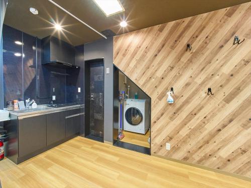 a kitchen with a wooden wall with a washing machine at Shimbashi Hotel Sho in Tokyo