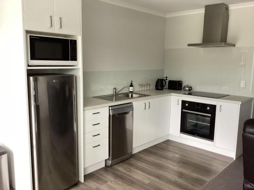 a kitchen with white cabinets and a stainless steel refrigerator at Modern and stylish in Meyer in Alexandra