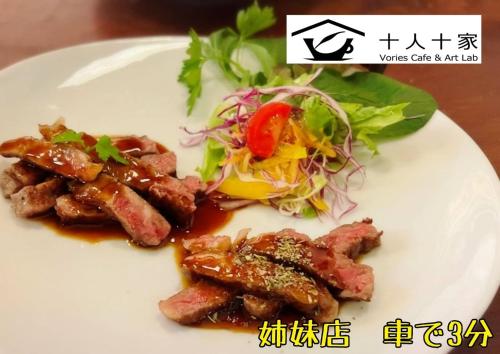 a plate of food with meat and a salad at 旅宿ありときりぎりす-近江八幡中心部で観光にお勧め in Omihachiman