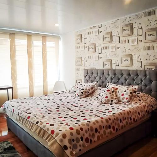 ein Schlafzimmer mit einem großen Bett und einer Wand mit Bildern in der Unterkunft Casa Vacacional Alejandria in Paipa