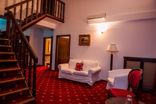a living room with a white couch and a staircase at Emire Boutique in Zărneşti