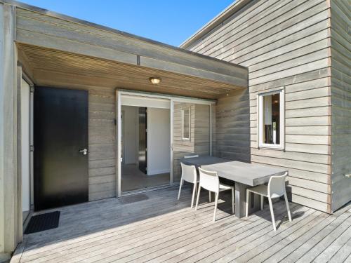 a patio with a table and chairs on a deck at The Weekender - Omaha Holiday Home in Warkworth