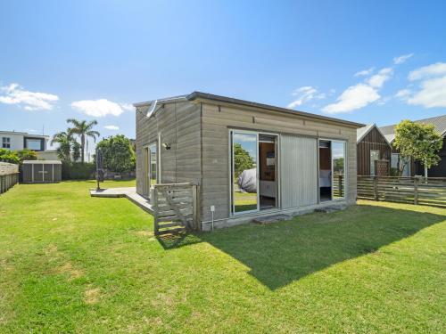 a small house in a yard with a grass field at The Weekender - Omaha Holiday Home in Warkworth