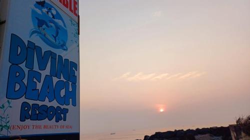 a sign on the beach with the sunset in the background at Divine Beach Resorts in Puducherry