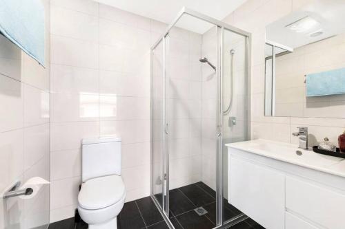 a white bathroom with a toilet and a shower at Modern New 3BR Townhouse with Free Parking in Belconnen