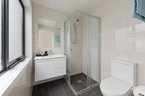 a bathroom with a shower and a toilet and a sink at Modern New 3BR Townhouse with Free Parking in Belconnen