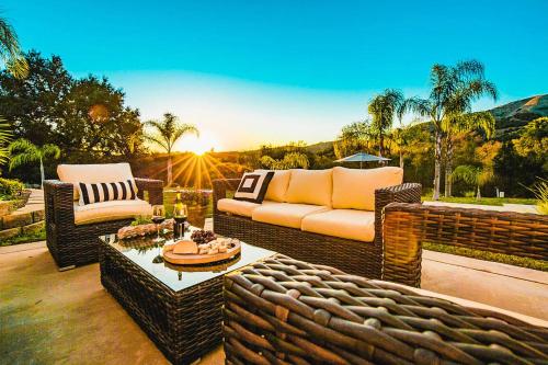 a patio with wicker chairs and a couch and a table at Grapevine by AvantStay Secluded 5BR Villa 4 Acres of Vineyards Avo Groves in Temecula