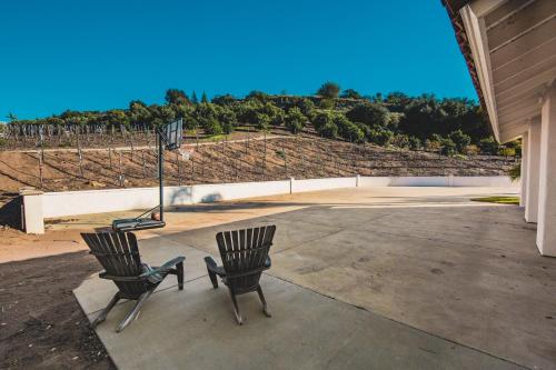 two black chairs sitting on a patio with a basketball hoop at Grapevine by AvantStay Secluded 5BR Villa 4 Acres of Vineyards Avo Groves in Temecula