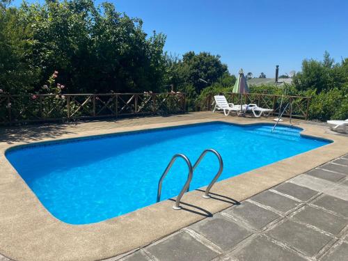 a swimming pool with blue water in a yard at Cabaña Quillón El Campito in Quillón