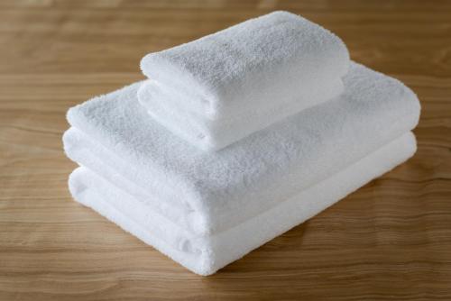 a stack of white towels on a wooden table at THE MACHIYA KAZAHAYA in Kyoto
