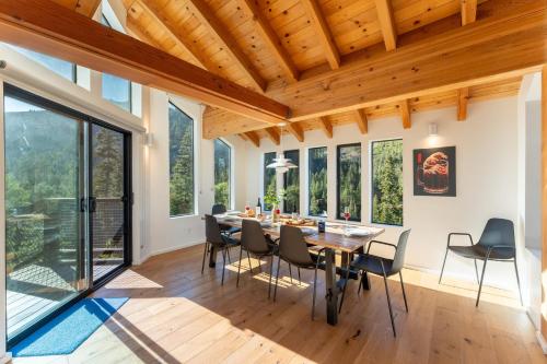 a dining room with a table and chairs and windows at Trapper by AvantStay A Interior Design w Sauna in Alpine Meadows