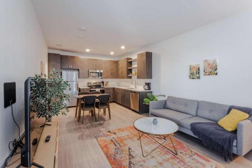 TWO Luxe CozySuites in Downtown Cincinnati في سينسيناتي: غرفة معيشة مع أريكة وطاولة ومطبخ