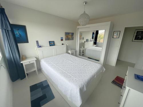 une chambre blanche avec un lit et un miroir dans l'établissement T2 Confortable avec Balcon, Parking et Équipements, Centre Arcachon, Proche Plage et Casino - FR-1-474-72, à Arcachon