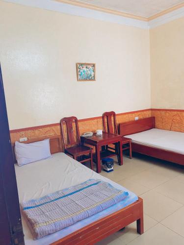 a room with two beds and two chairs and a table at Nhà nghỉ FAMY in Móng Cái