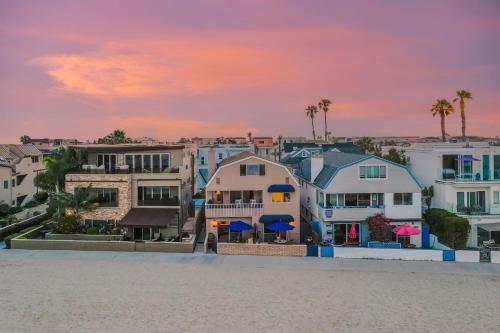 a group of houses on the beach at sunset at Bay View I by AvantStay Stylish Mission Beach Home on the Sand in San Diego