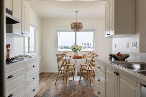 a kitchen with a table with chairs and a window at Bay View I by AvantStay Stylish Mission Beach Home on the Sand in San Diego