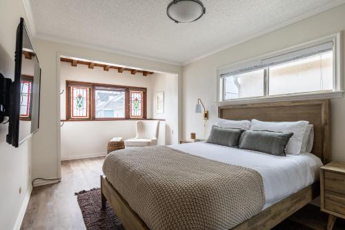 a bedroom with a bed and a chair and windows at Bay View I by AvantStay Stylish Mission Beach Home on the Sand in San Diego