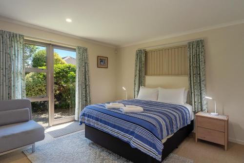 a bedroom with a bed and a chair and a window at Casa Bella - Nelson Holiday Home in Nelson