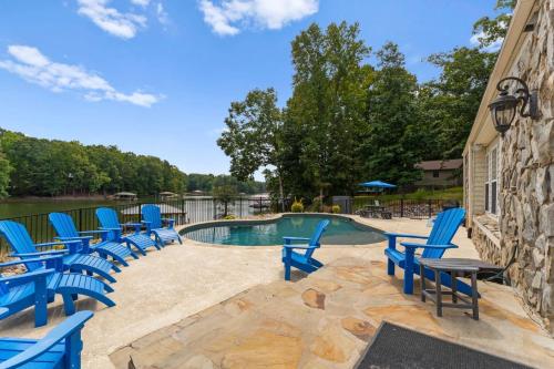 a swimming pool with blue chairs next to a building at Whitetail Cove by AvantStay Lakefront w Pool Private Dock Sleeps 20 in Terrell