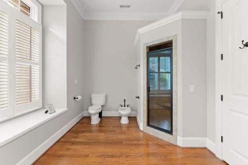 a white bathroom with a toilet and a window at Whitetail Cove by AvantStay Lakefront w Pool Private Dock Sleeps 20 in Terrell