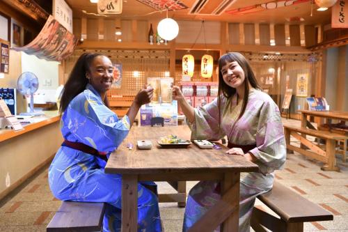 two women in kimonos sitting at a table in a store at Yunogo Onsen HOTEL YUNOMORI BISYUNKAKU in Mimasaka
