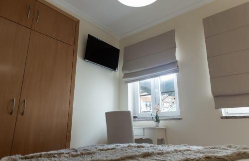 a bedroom with a bed and a desk and a window at Casa d'Avenida in Manteigas