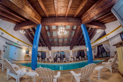 a pool in a large room with chairs and a table at Emire Boutique in Zărneşti