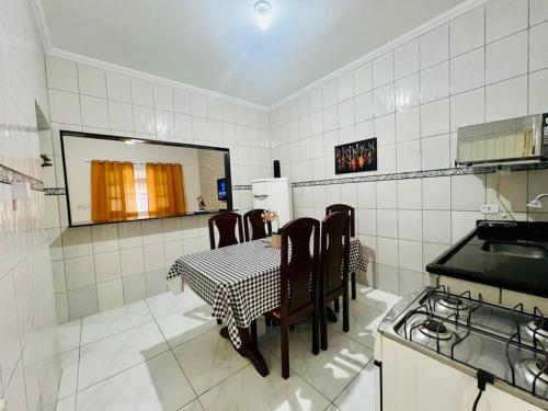 eine Küche mit Tisch und Stühlen in einem Zimmer in der Unterkunft Casa de 2 Quartos à 5 min a Pé da Praia, com Churrasqueira e 3 Vagas de Garagem in Praia Grande
