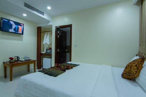 a bedroom with a white bed and a television at Rose Emerald Hotel in Phnom Penh