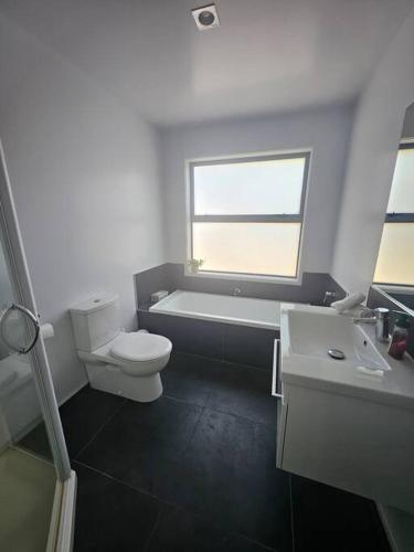 Un baño con inodoro, bañera y lavabo. en Coastal Beach Haven, en Papamoa