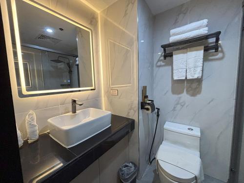 a bathroom with a sink and a toilet and a mirror at Lido De Paris Hotel in Manila