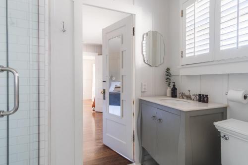 a white bathroom with a sink and a mirror at Topaz By AvantStay Adorable Cottage Walking Distance to Beach w Large Patio in San Diego