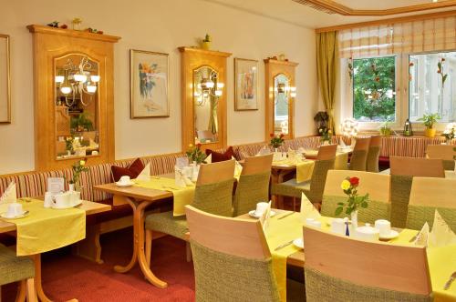 a restaurant with tables and chairs with yellow tablecloths at Park Hotel Laim in Munich