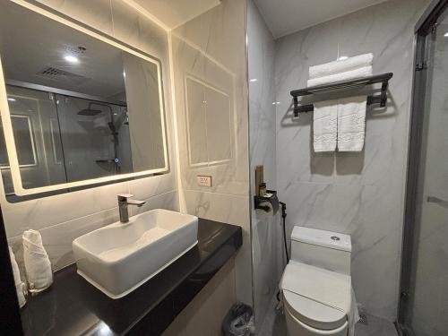 a bathroom with a sink and a toilet and a mirror at Lido De Paris Hotel in Manila
