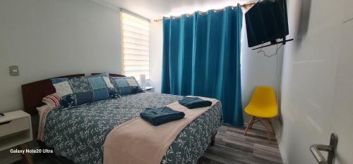 a bedroom with a bed with blue curtains and a yellow chair at Departamento 11 arriendo por dia Arica SOL primer piso in Arica
