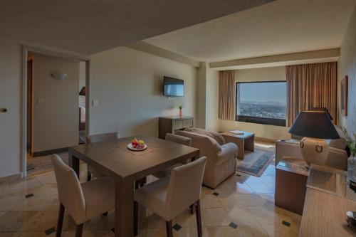 a living room with a table and chairs and a living room at Holiday Inn Puebla La Noria by IHG in Puebla