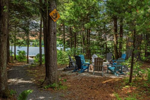 a group of chairs sitting around a table in the woods at Tranquil Waterside by AvantStay Lakefront Dock Game Room Views in Pocono Summit