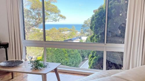a living room with a large window with a view of the ocean at Copacabana Tranquil Escape Views, Pet Friendly On Request Accom Holidays in Copacabana