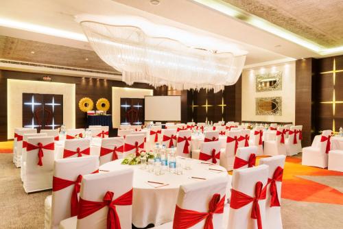 a banquet hall with white tables and red bows at Aauris in Kolkata