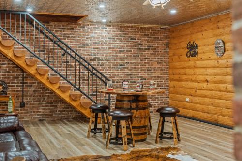 a bar in a room with a staircase and stools at The Bigwood Cabin by AvantStay Hot Tub Firepit Pool Table Private Yard in Long Pond