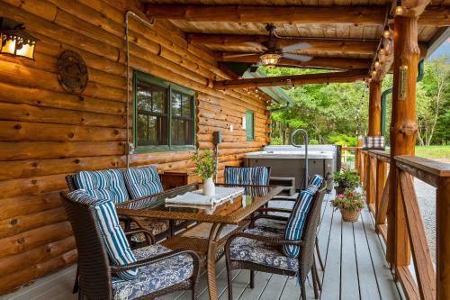 a wooden deck with a wooden table and chairs at The Bigwood Cabin by AvantStay Hot Tub Firepit Pool Table Private Yard in Long Pond